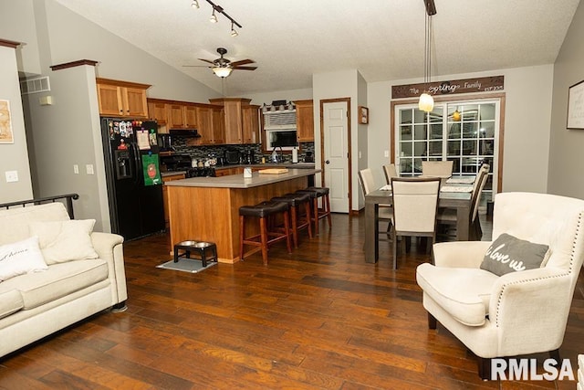 kitchen featuring lofted ceiling, tasteful backsplash, pendant lighting, a kitchen island, and black appliances