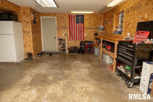 garage featuring white refrigerator and a workshop area