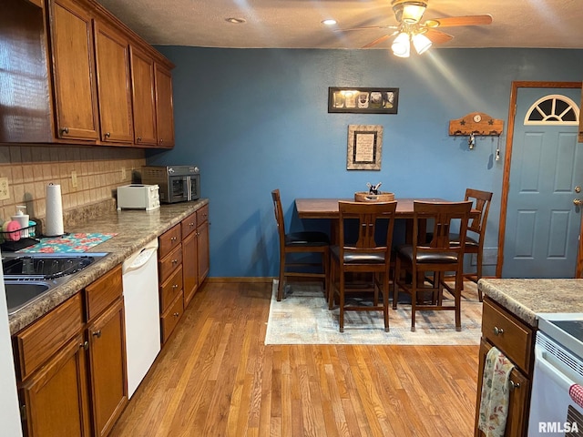 kitchen featuring tasteful backsplash, light wood-type flooring, dishwasher, and ceiling fan