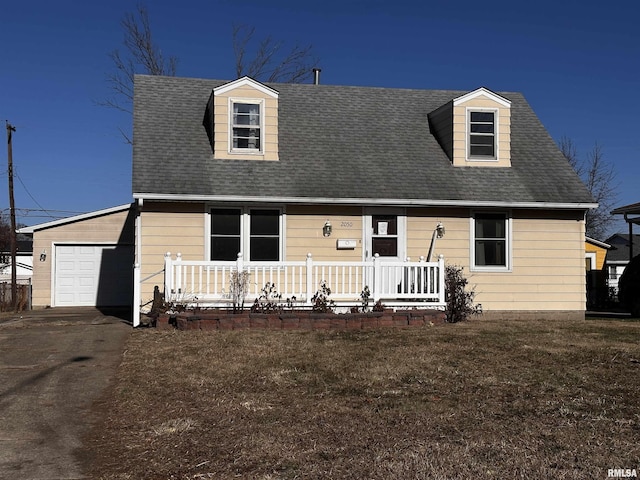 new england style home with an attached garage, covered porch, a shingled roof, driveway, and a front lawn