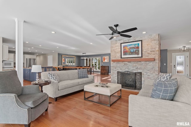 living room with ornate columns, ceiling fan, a fireplace, and light hardwood / wood-style floors