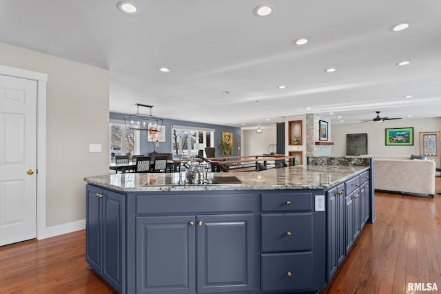 kitchen featuring sink, a center island, blue cabinets, dark hardwood / wood-style flooring, and decorative light fixtures