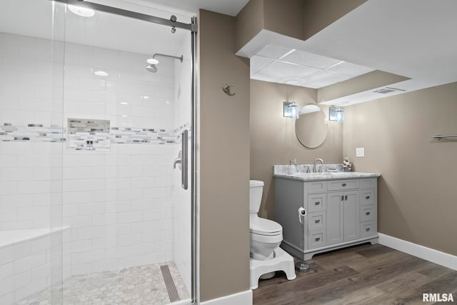 bathroom with hardwood / wood-style flooring, vanity, toilet, and a shower with door