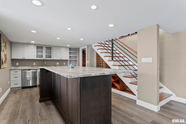 kitchen with stainless steel dishwasher, light hardwood / wood-style flooring, a kitchen island, and white cabinets