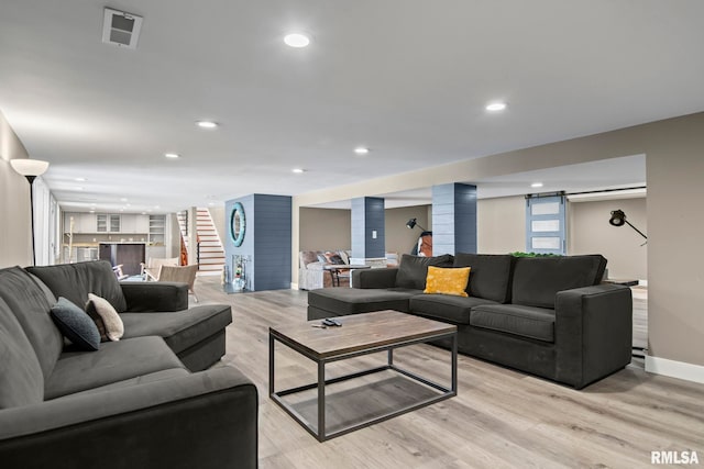 living room featuring light wood-type flooring, a barn door, and ornate columns