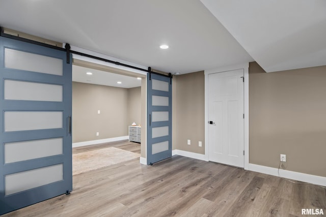 basement with wood-type flooring and a barn door