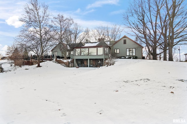 snow covered house featuring a sunroom