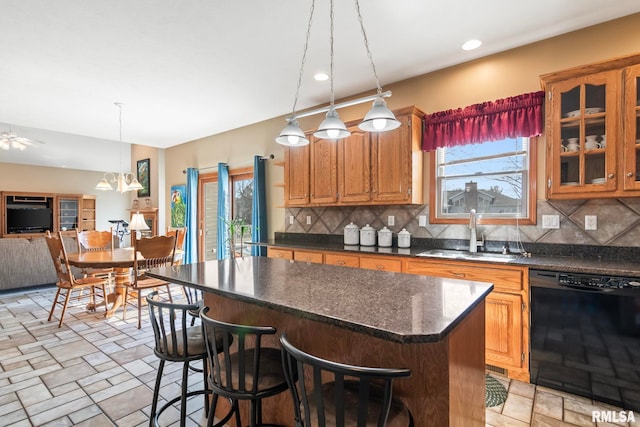 kitchen with dishwasher, a breakfast bar area, a sink, and glass insert cabinets