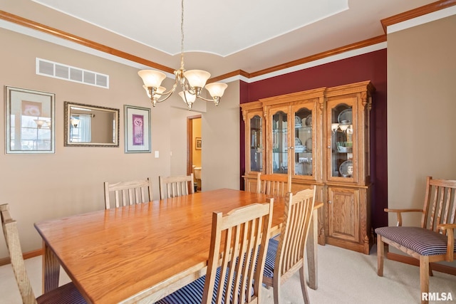 dining room featuring ornamental molding, visible vents, a notable chandelier, and light carpet