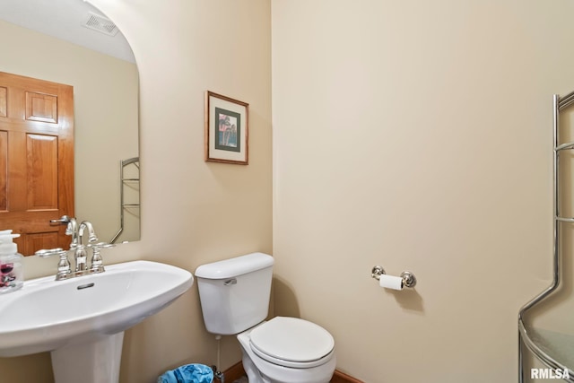 bathroom featuring toilet, a sink, and visible vents