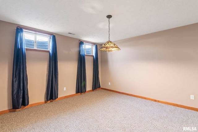 carpeted spare room with a wealth of natural light, visible vents, and baseboards