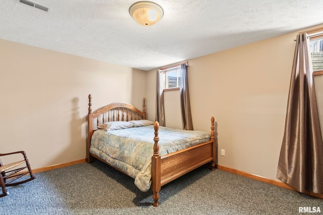 bedroom with a textured ceiling, carpet flooring, visible vents, and baseboards