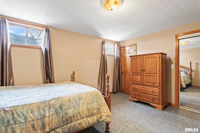 bedroom featuring light carpet, a textured ceiling, and baseboards