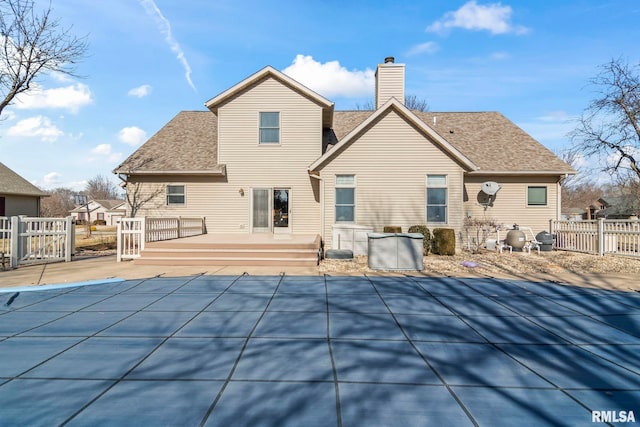 back of property featuring a shingled roof, fence, a wooden deck, a fenced in pool, and a chimney