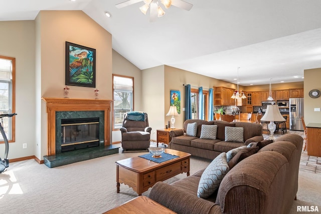 living area featuring a high end fireplace, light carpet, high vaulted ceiling, baseboards, and ceiling fan with notable chandelier