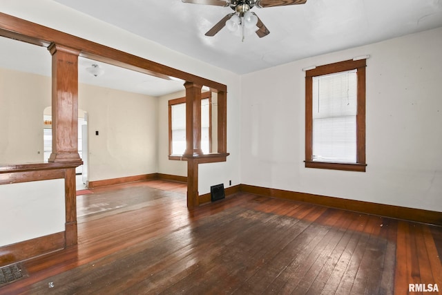 unfurnished living room featuring ceiling fan, dark hardwood / wood-style flooring, decorative columns, and a healthy amount of sunlight