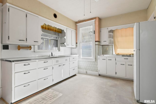 kitchen with white fridge, sink, tasteful backsplash, and white cabinetry