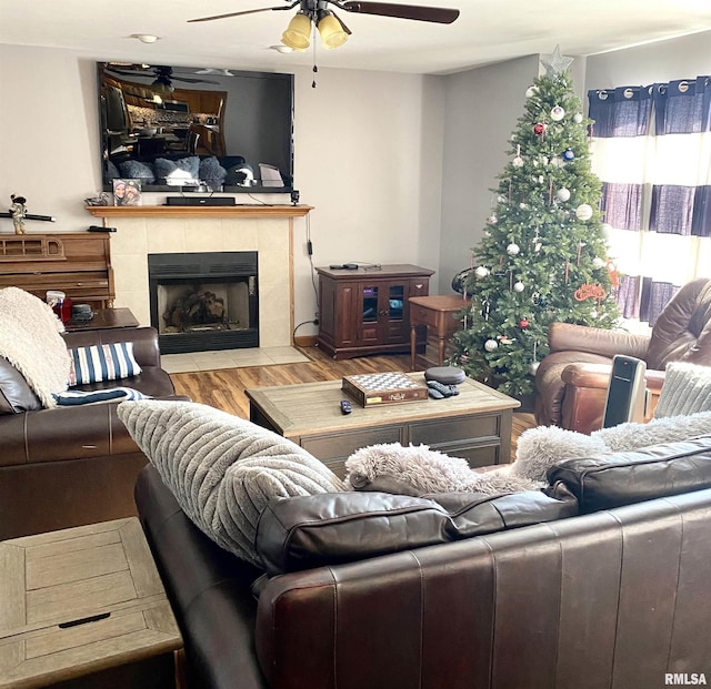 living room with a tiled fireplace, ceiling fan, and hardwood / wood-style floors