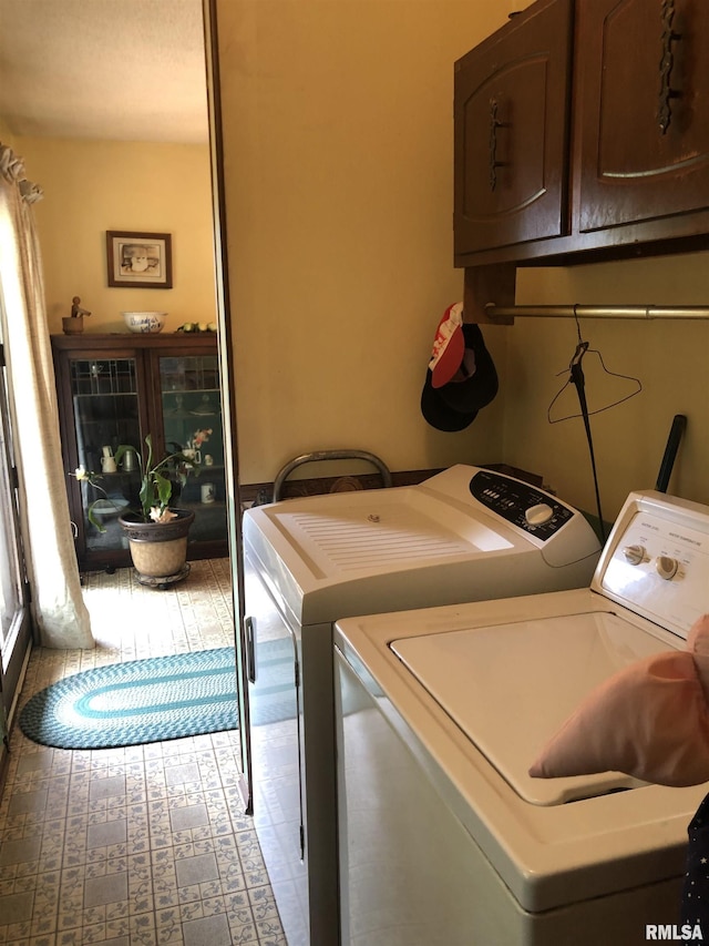 clothes washing area with cabinets and washing machine and clothes dryer