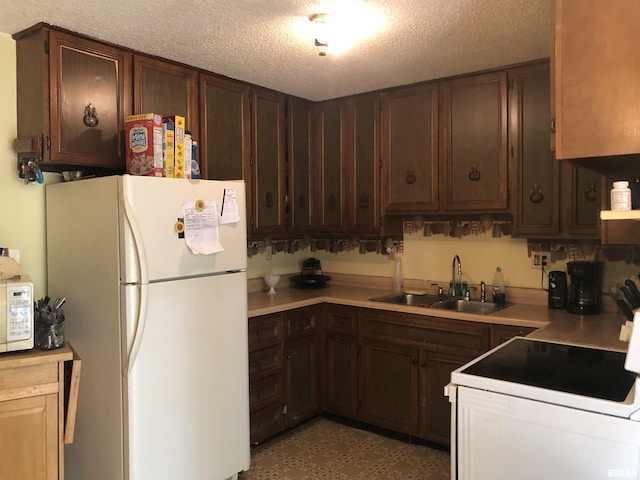 kitchen featuring white appliances, a textured ceiling, dark brown cabinets, and sink