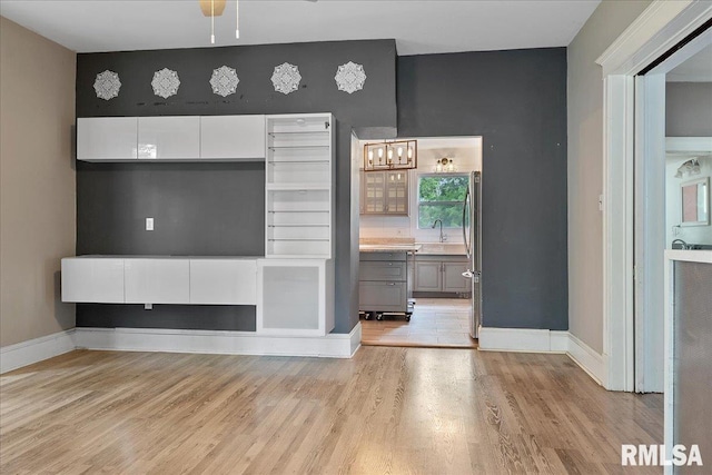 unfurnished living room with sink, ceiling fan, and light hardwood / wood-style floors