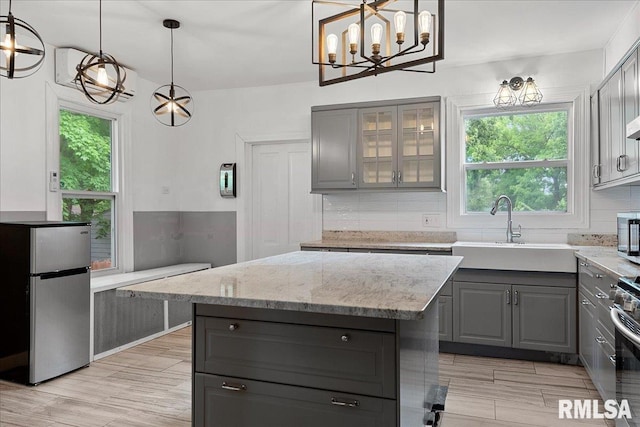 kitchen with hanging light fixtures, a center island, gray cabinets, appliances with stainless steel finishes, and sink