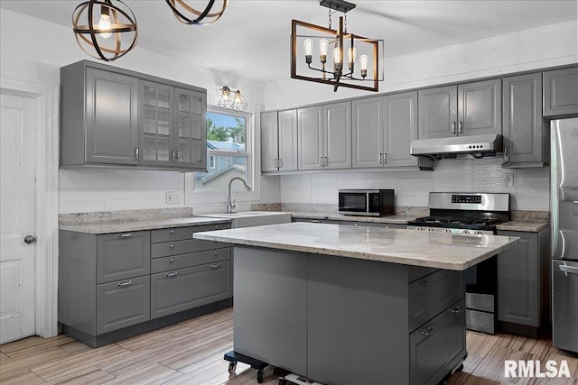 kitchen with a center island, pendant lighting, gray cabinets, and appliances with stainless steel finishes