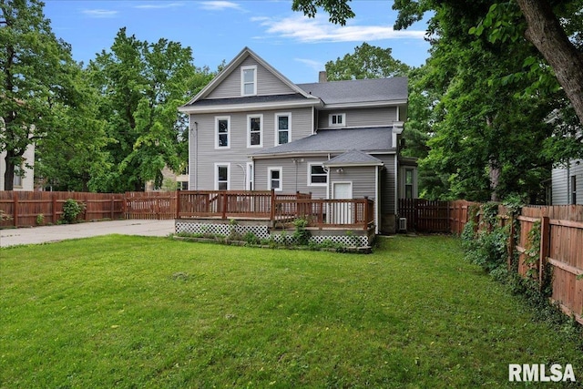 back of property with a deck and a yard