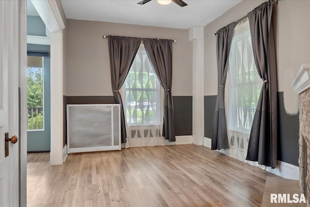 unfurnished room featuring radiator, ceiling fan, and light hardwood / wood-style flooring