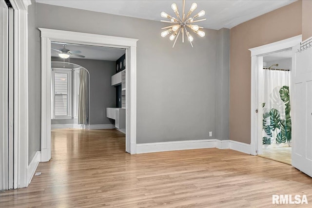 interior space featuring light wood-type flooring and ceiling fan with notable chandelier