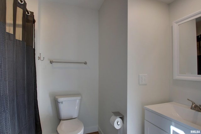 bathroom featuring toilet, vanity, and curtained shower