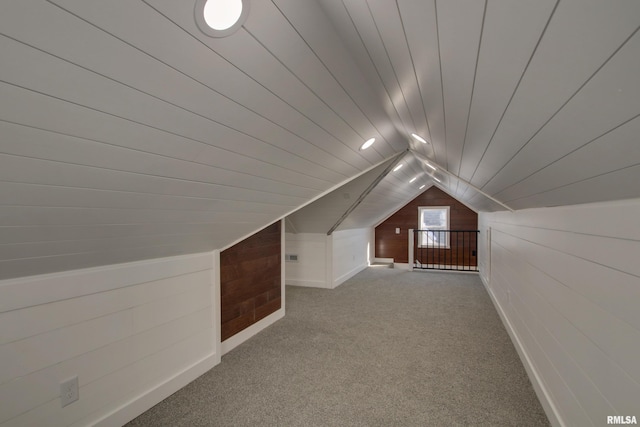 bonus room with light carpet, vaulted ceiling, and wooden walls