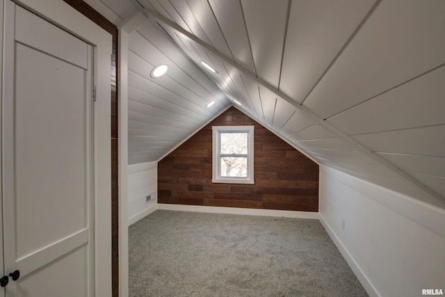 additional living space with carpet floors, wood walls, and vaulted ceiling