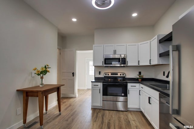 kitchen featuring white cabinets, appliances with stainless steel finishes, sink, and light hardwood / wood-style floors