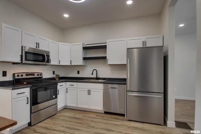 kitchen with light hardwood / wood-style floors, decorative backsplash, sink, white cabinetry, and stainless steel appliances