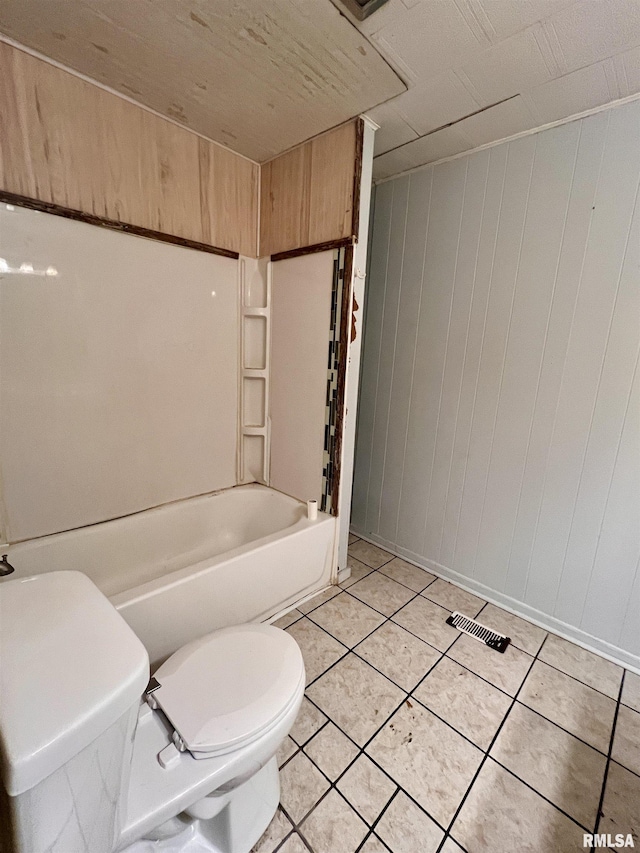 bathroom with toilet, tile patterned flooring, and wooden walls