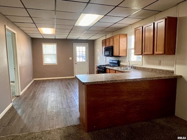 kitchen with a drop ceiling, dark hardwood / wood-style floors, black appliances, sink, and a healthy amount of sunlight