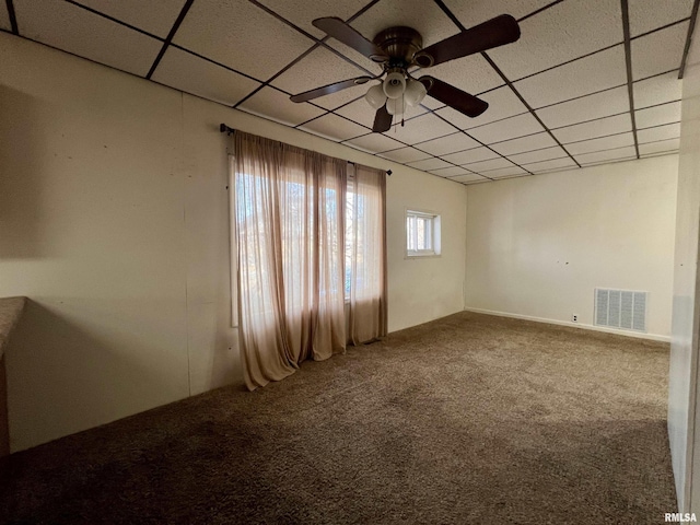 carpeted empty room with ceiling fan and a paneled ceiling