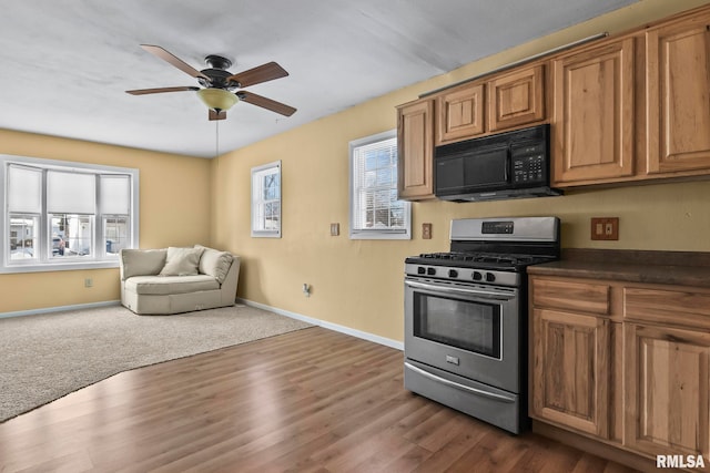 kitchen with black microwave, open floor plan, brown cabinetry, dark countertops, and gas range