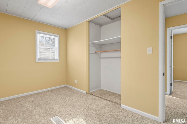 unfurnished bedroom featuring carpet floors, visible vents, baseboards, and a closet