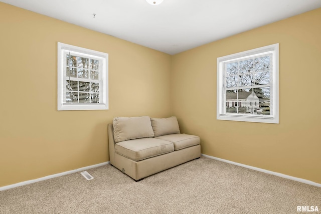 living area featuring light carpet, visible vents, and baseboards