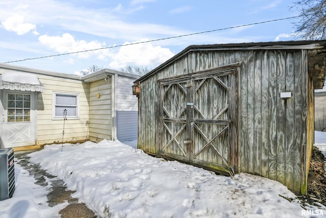 snow covered structure featuring an outbuilding