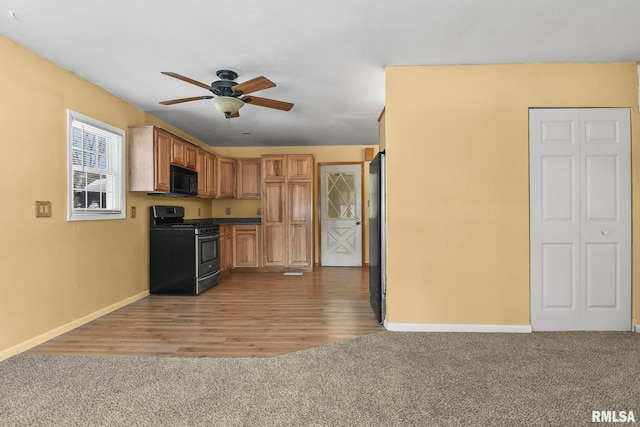 kitchen featuring baseboards, a ceiling fan, stainless steel gas range, carpet, and black microwave