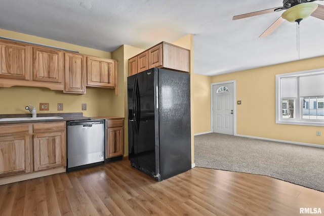 kitchen featuring dishwasher, dark countertops, ceiling fan, black refrigerator with ice dispenser, and a sink