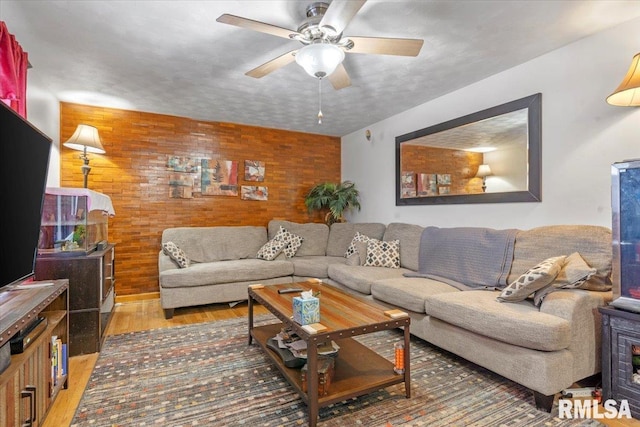 living room featuring ceiling fan, wooden walls, a textured ceiling, and hardwood / wood-style flooring