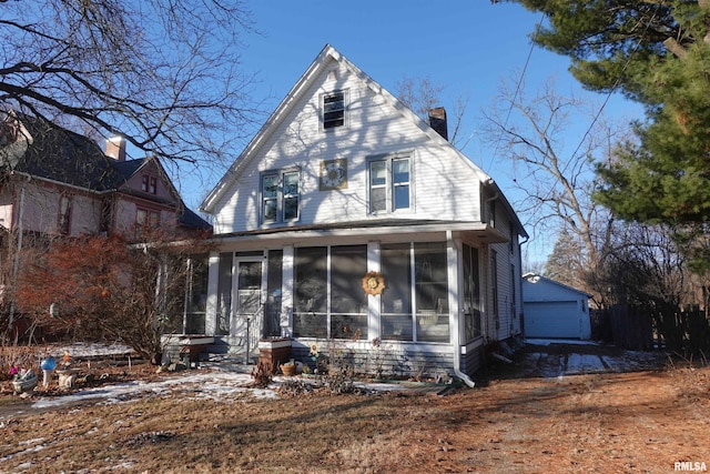 view of front of home featuring a garage, a sunroom, and an outdoor structure