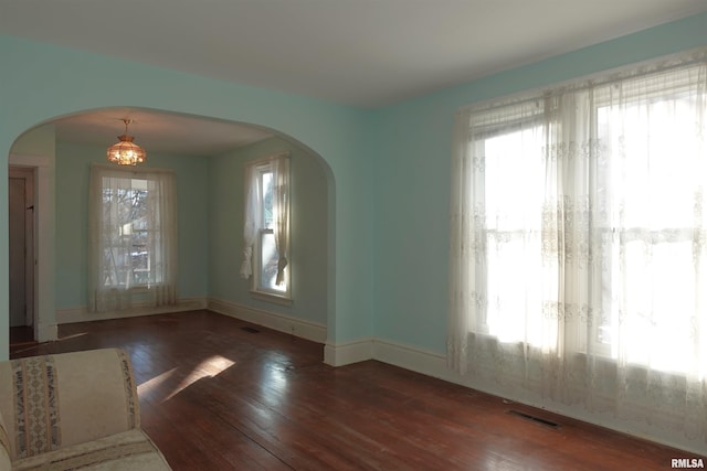 unfurnished dining area featuring a chandelier and dark hardwood / wood-style floors