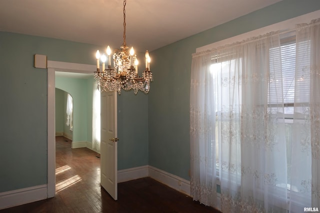 unfurnished dining area with dark wood-type flooring and a chandelier