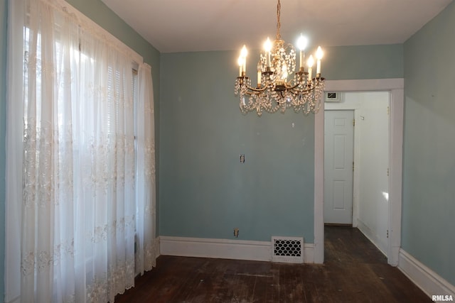 unfurnished dining area featuring dark wood-type flooring and a notable chandelier