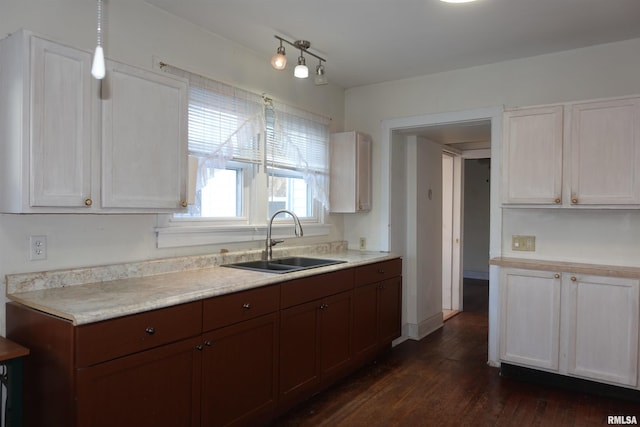 kitchen with dark hardwood / wood-style flooring, pendant lighting, white cabinets, and sink